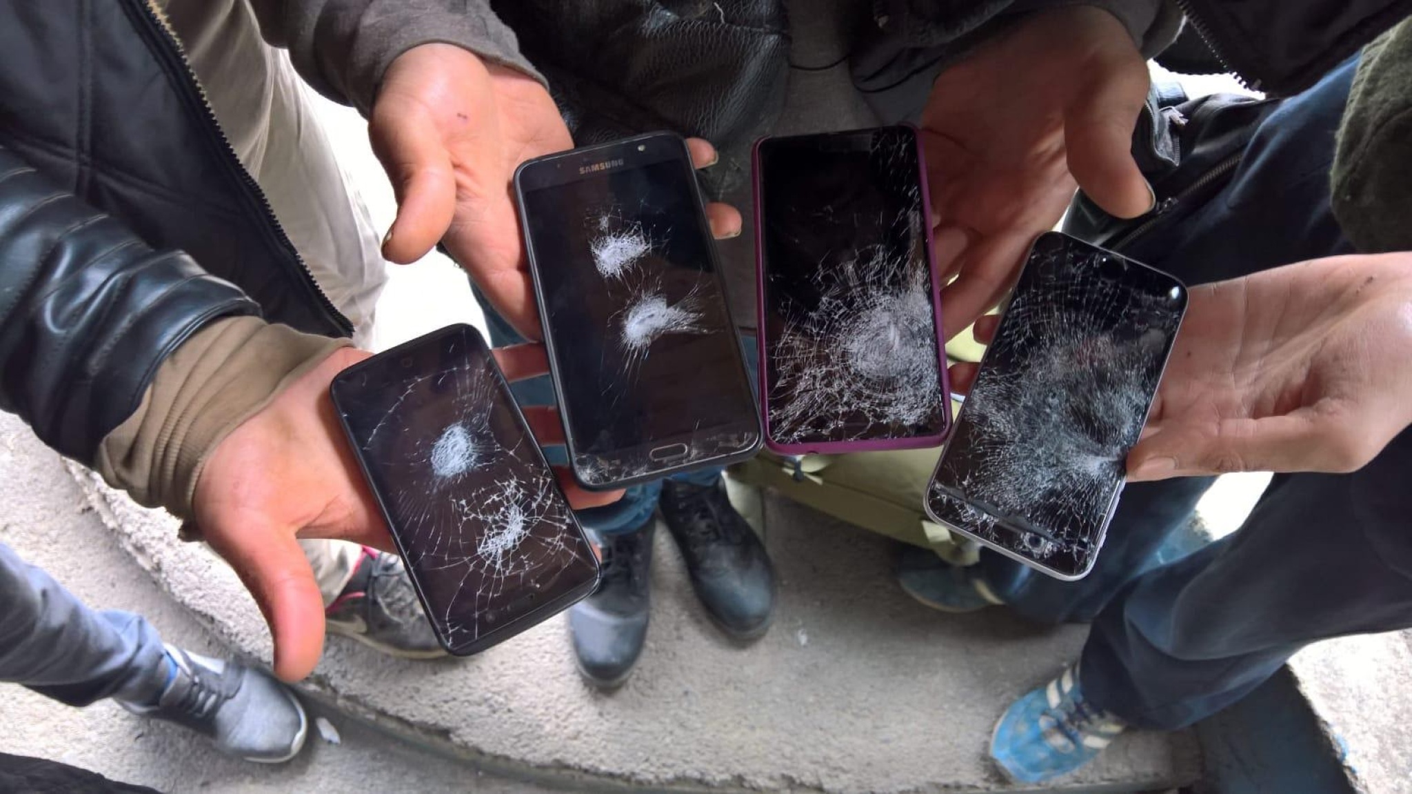 Men showing damaged phones after being pushed back from Croatia to BiH, July 2018. Photograph by Jack Sapoch.